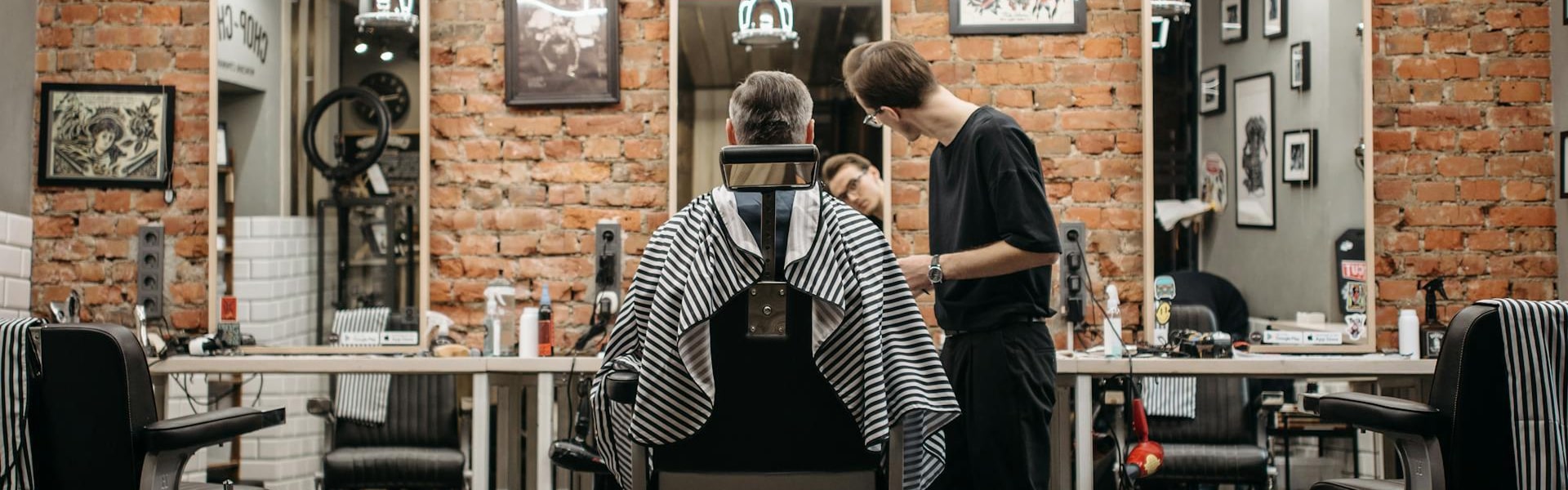 Barber servicing a male client sitting in a chair inside a traditional barbershop
