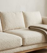 Cream bouclé sofa with a knitted throw
