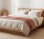 Bedroom with linen bedding and a warm bedside table lamp